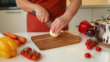 mani di anziano 60s femmina chopping fresco cipolla su di legno tavola mentre preparazione italiano pasta con verdure e la minestra video