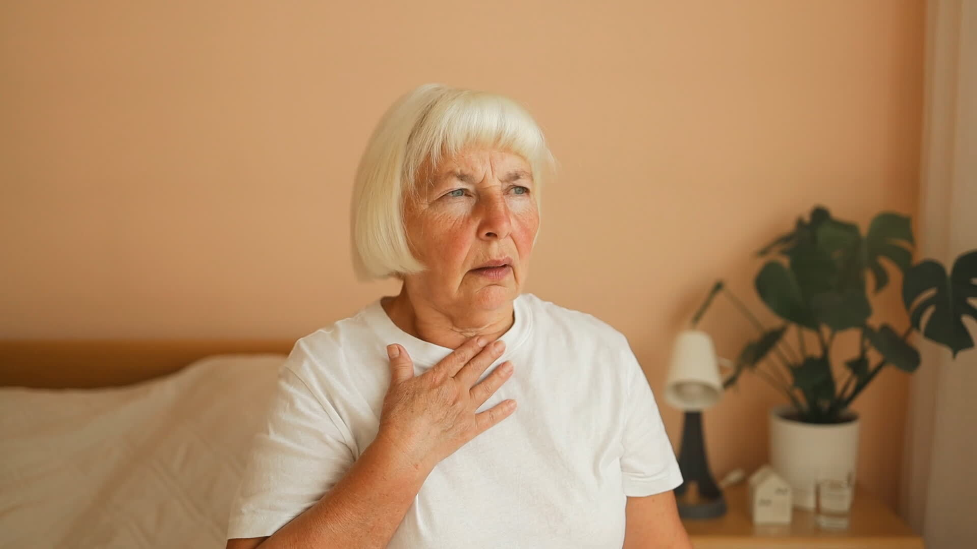 Close up side view of ill senior woman putting hand on chest, feels