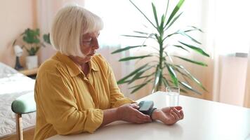 senior kvinna är kontroll blod tryck och hjärta Betygsätta med digital tryck mätare förbi själv på Hem. äldre kvinna tar vård för hälsa. hälsa och medicinsk begrepp. video