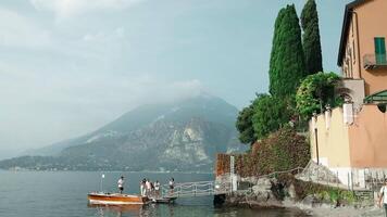 como, Itália - 12 Outubro 2023. panorâmico Visão do pessoas turistas mulheres e homens amigos borda uma luxo motor barco para uma passeio em lago como em uma quente verão dia como, torno. Visão do a cais e edifícios video