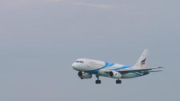 PHUKET, THAILAND - NOVEMBER 28, 2019 - Bangkok Air plane approaching landing at Phuket International Airport, long shot. Airliner flies over the treetops. Passenger flight arriving video