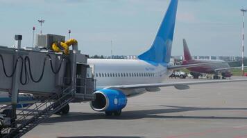 SAINT PETERSBURG, RUSSIA - JULY 26, 2022. Aircraft Boeing 737 of Pobeda taxiing on the runway at Pulkovo airport, St. Petersburg. Tractor pulling an airliner. Telescopic gangway at the terminal video