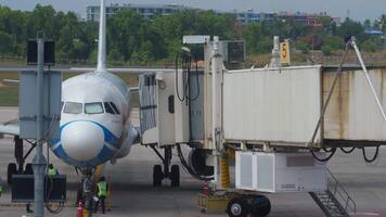 PHUKET, THAILAND - FEBRUARY 28, 2023. Airbus A320 of Bangkok Air with Samui livery at the terminal of Phuket airport. Telescopic gangway docked to an airplane. Preparation of airplane before flight. video