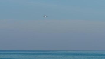 lungo tiro di un aereo si avvicina per terra. aereo di linea mosche al di sopra di il blu mare, discesa. turboelica vettore nel il cielo video