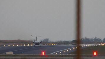 Private jet plane taking off, rear view through the fence. Runway lighting with landing lights video