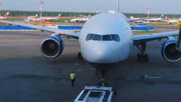 Moskou, Russisch federatie - mei 26, 2015. visie van de terminal venster naar de schort van domodedovo luchthaven. trekker trekken wide-body passagiersvliegtuig transnaero op taxi weg video