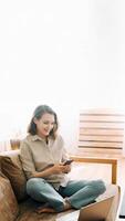 Productive Millennial Workday. Smiling woman looks at phone, reads messages, multitasks with laptop during a virtual meeting. Efficient Remote Work Modern Technology and Business Communication Concept photo