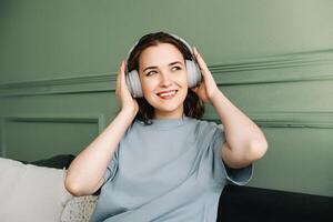 Relaxed Weekend Vibes. Happy Woman Enjoying Music on the Couch. Music Therapy. Woman in Wireless Headphones Embracing Weekend Tunes photo
