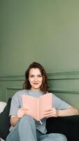Happy young woman reading a book sitting comfortably on the couch enjoying a relaxing evening. Relaxed young woman enjoying a relaxing evening reading sitting on the couch. Rest and relaxation photo