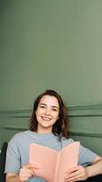 A happy young woman reading a book, sitting on the couch, enjoying a relaxing evening out photo