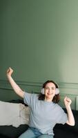 alegre milenario joven mujer vistiendo inalámbrico auriculares escuchando a música, baile, y disfrutando su gratis tiempo. despreocupado melodías alegre joven mujer bailando a música foto