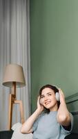 Happy young woman wearing wireless headphones listening to music while enjoying some free time on the couch. Joyful Moments. Woman Relaxing and Listening to Music on the Sofa photo