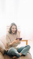 Joyful millennial woman with an open mouth, captivated by her phone. Engaged in playing mobile games, reading messages, and lively chatting in a chat room. Expressive Smartphone Interaction photo