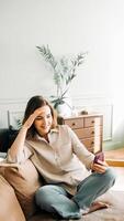 Euphoric Tech Delight. Joyful millennial woman laughs while engrossed in her phone. Reading messages, playing games, and savoring free time. Expressive Laughter Amidst Smartphone Enjoyment. photo