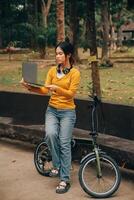 Happy young Asian woman while riding a bicycle in a city park. She smiled using the bicycle of transportation. Environmentally friendly concept. photo