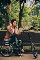 Happy young Asian woman while riding a bicycle in a city park. She smiled using the bicycle of transportation. Environmentally friendly concept. photo