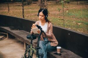 Happy young Asian woman while riding a bicycle in a city park. She smiled using the bicycle of transportation. Environmentally friendly concept. photo