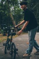 Young handsome bearded man taking a break while travelling the city with his bicycle using his digital tablet looking away thoughtfully photo