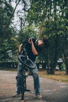 joven hermoso barbado hombre tomando un descanso mientras de viaje el ciudad con su bicicleta utilizando su digital tableta mirando lejos pensativamente foto