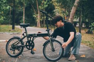 Young handsome bearded man taking a break while travelling the city with his bicycle using his digital tablet looking away thoughtfully photo