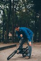 Young handsome bearded man taking a break while travelling the city with his bicycle using his digital tablet looking away thoughtfully photo