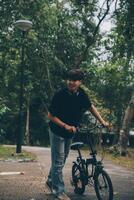 Young handsome bearded man taking a break while travelling the city with his bicycle using his digital tablet looking away thoughtfully photo