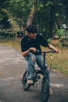 joven hermoso barbado hombre tomando un descanso mientras de viaje el ciudad con su bicicleta utilizando su digital tableta mirando lejos pensativamente foto