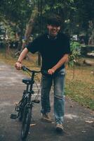 joven hermoso barbado hombre tomando un descanso mientras de viaje el ciudad con su bicicleta utilizando su digital tableta mirando lejos pensativamente foto