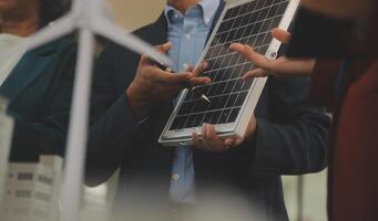 Close-up at tablet, Engineers pointing at tablet with their hands. To jointly design the use of renewable energy with wind and solar energy. Concept of using renewable energy. photo