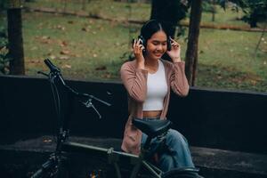 Happy young Asian woman while riding a bicycle in a city park. She smiled using the bicycle of transportation. Environmentally friendly concept. photo