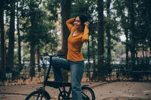 Happy young Asian woman while riding a bicycle in a city park. She smiled using the bicycle of transportation. Environmentally friendly concept. photo