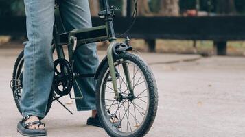 contento joven asiático mujer mientras montando un bicicleta en un ciudad parque. ella sonrió utilizando el bicicleta de transporte. ambientalmente simpático concepto. foto