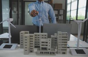 Close-up at tablet, Engineers pointing at tablet with their hands. To jointly design the use of renewable energy with wind and solar energy. Concept of using renewable energy. photo