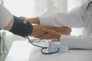masculino médico usos un sangre presión monitor a cheque el cuerpo presión y legumbres de el pacientes quien ven a el hospital para chequeos, médico tratamiento y salud cuidado concepto. foto