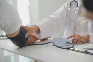 Male doctor uses a blood pressure monitor to check the body pressure and pulse of the patients who come to the hospital for check-ups, Medical treatment and health care concept. photo