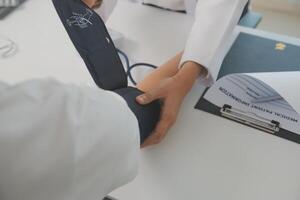 Male doctor uses a blood pressure monitor to check the body pressure and pulse of the patients who come to the hospital for check-ups, Medical treatment and health care concept. photo