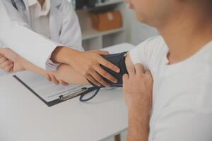 masculino médico usos un sangre presión monitor a cheque el cuerpo presión y legumbres de el pacientes quien ven a el hospital para chequeos, médico tratamiento y salud cuidado concepto. foto