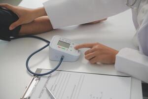 Male doctor uses a blood pressure monitor to check the body pressure and pulse of the patients who come to the hospital for check-ups, Medical treatment and health care concept. photo