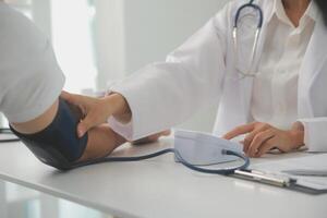 Male doctor uses a blood pressure monitor to check the body pressure and pulse of the patients who come to the hospital for check-ups, Medical treatment and health care concept. photo