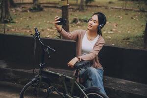 Happy young Asian woman while riding a bicycle in a city park. She smiled using the bicycle of transportation. Environmentally friendly concept. photo