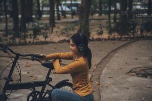 Happy young Asian woman while riding a bicycle in a city park. She smiled using the bicycle of transportation. Environmentally friendly concept. photo