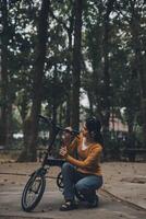 Happy young Asian woman while riding a bicycle in a city park. She smiled using the bicycle of transportation. Environmentally friendly concept. photo