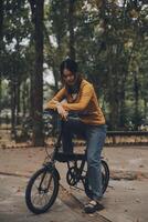 Happy young Asian woman while riding a bicycle in a city park. She smiled using the bicycle of transportation. Environmentally friendly concept. photo