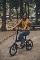 Happy young Asian woman while riding a bicycle in a city park. She smiled using the bicycle of transportation. Environmentally friendly concept. photo