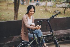 Happy young Asian woman while riding a bicycle in a city park. She smiled using the bicycle of transportation. Environmentally friendly concept. photo