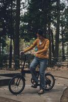 Happy young Asian woman while riding a bicycle in a city park. She smiled using the bicycle of transportation. Environmentally friendly concept. photo