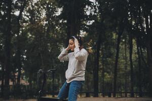 contento asiático joven mujer caminar y paseo bicicleta en parque, calle ciudad su sonriente utilizando bicicleta de transporte, eco amigable, personas estilo de vida concepto. foto