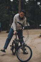 contento asiático joven mujer caminar y paseo bicicleta en parque, calle ciudad su sonriente utilizando bicicleta de transporte, eco amigable, personas estilo de vida concepto. foto