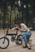 Happy Asian young woman walk and ride bicycle in park, street city her smiling using bike of transportation, ECO friendly, People lifestyle concept. photo