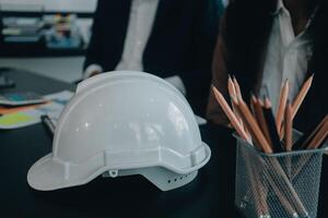 reunión de trabajo en equipo de ingenieros, trabajo de dibujo en la reunión de planos para el trabajo del proyecto con un socio en la construcción de modelos y herramientas de ingeniería en el concepto de sitio de trabajo, construcción y estructura. foto